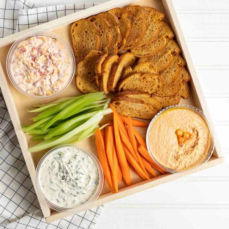 A tray of dips, hummus, carrots, celery and crostini