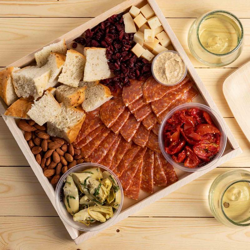 A tray of focaccia, chorizo, cheese, roasted tomatoes, artichoke hearts, almonds, dried cranberries and whole grain mustard